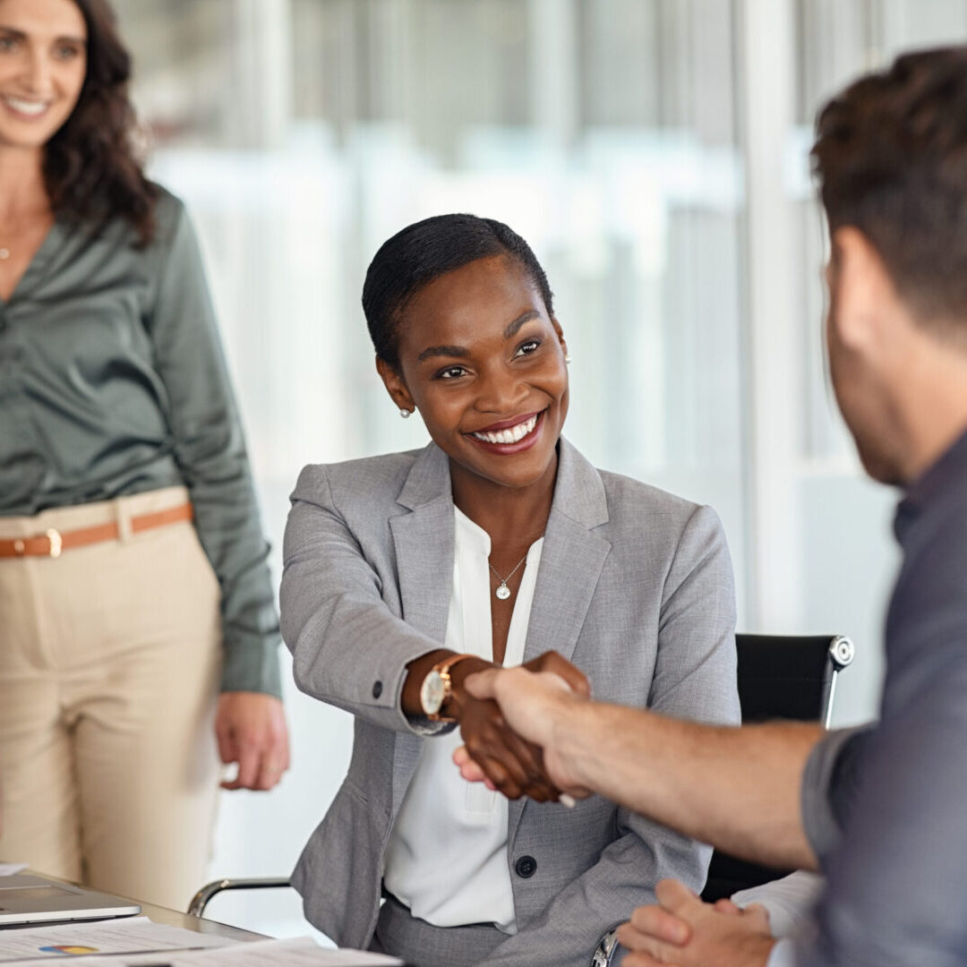 Mature black businesswoman shaking hands with new business partner Businesspeople shaking hands in a meeting.
