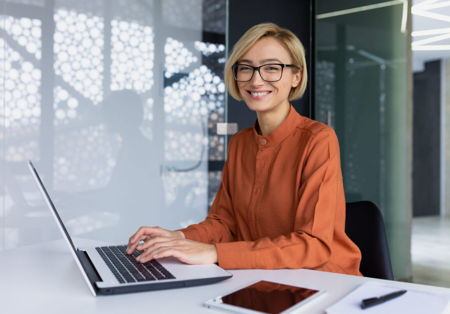 Smiling woman working on a laptop.